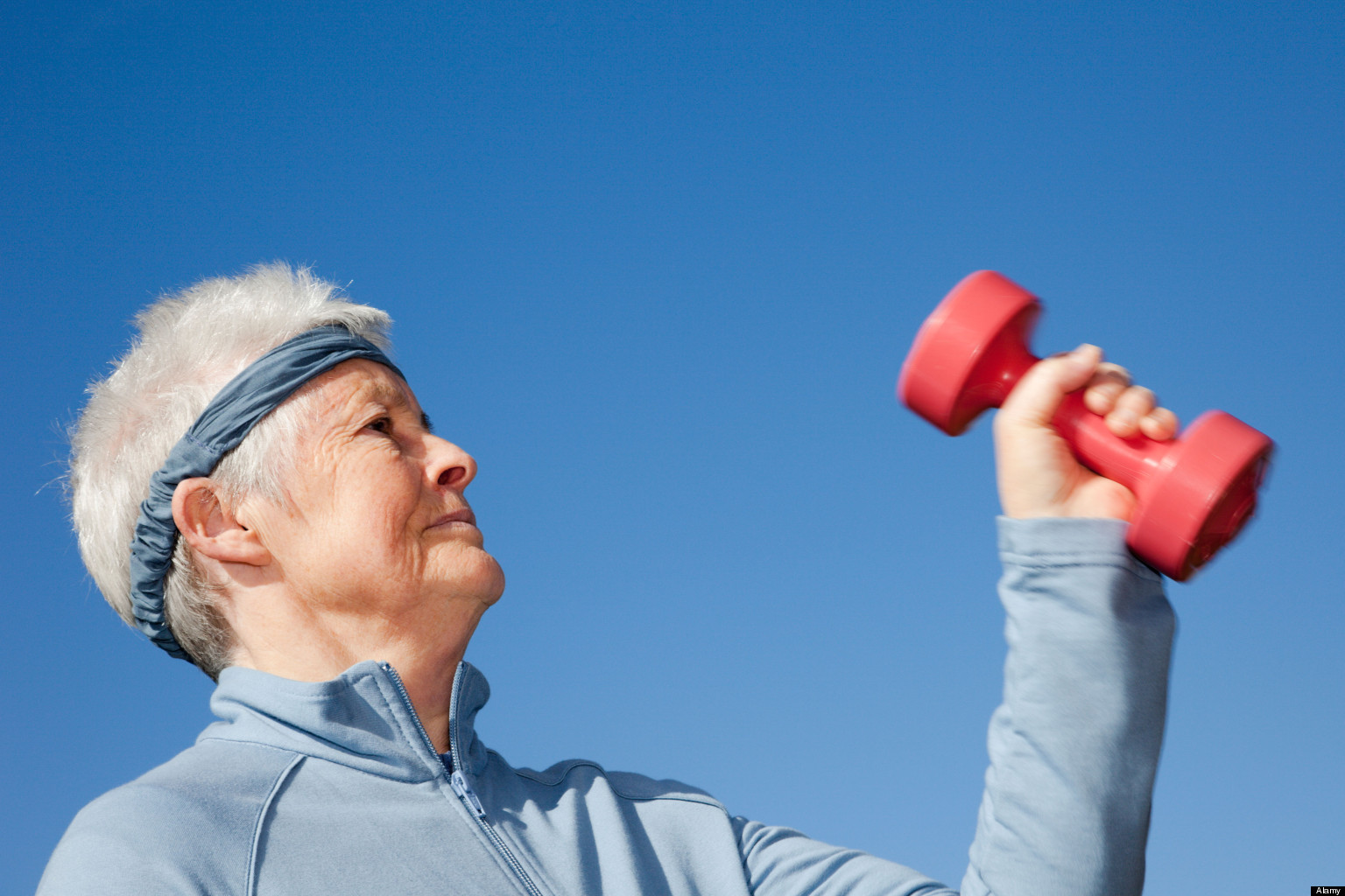 BJ5XG9 Britain, UK, Europe. Grey haired senior woman pensioner exercising with dumbbell hand weights to keep healthy